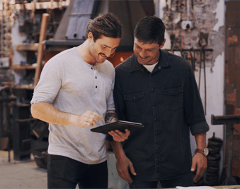 Two men smiling at a ipad